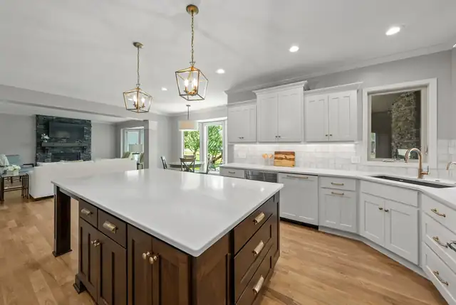 Kitchen remodel with a walnut-stained island, white quartz top, white perimeter cabinets and gold lantern pendants