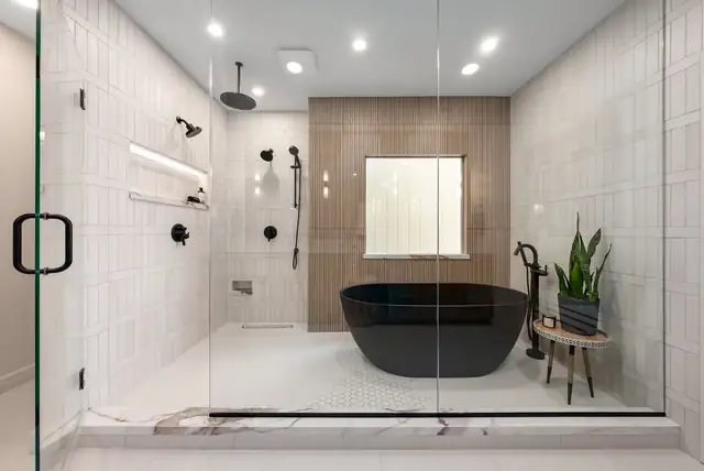 Bathroom remodel with a black freestanding tub inside a glass-enclosed wet room, white stacked tile and a wood-tile accent wall